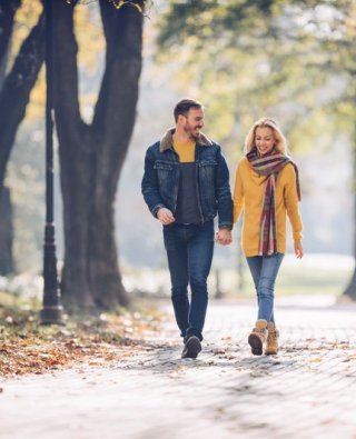 Couple walking through forest with Autumnal setting. 